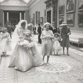 Принцесса Диана несет самую маленькую подружку невесты на руках  через залы Букингемского дворца. Рядом идет королева Елизавета